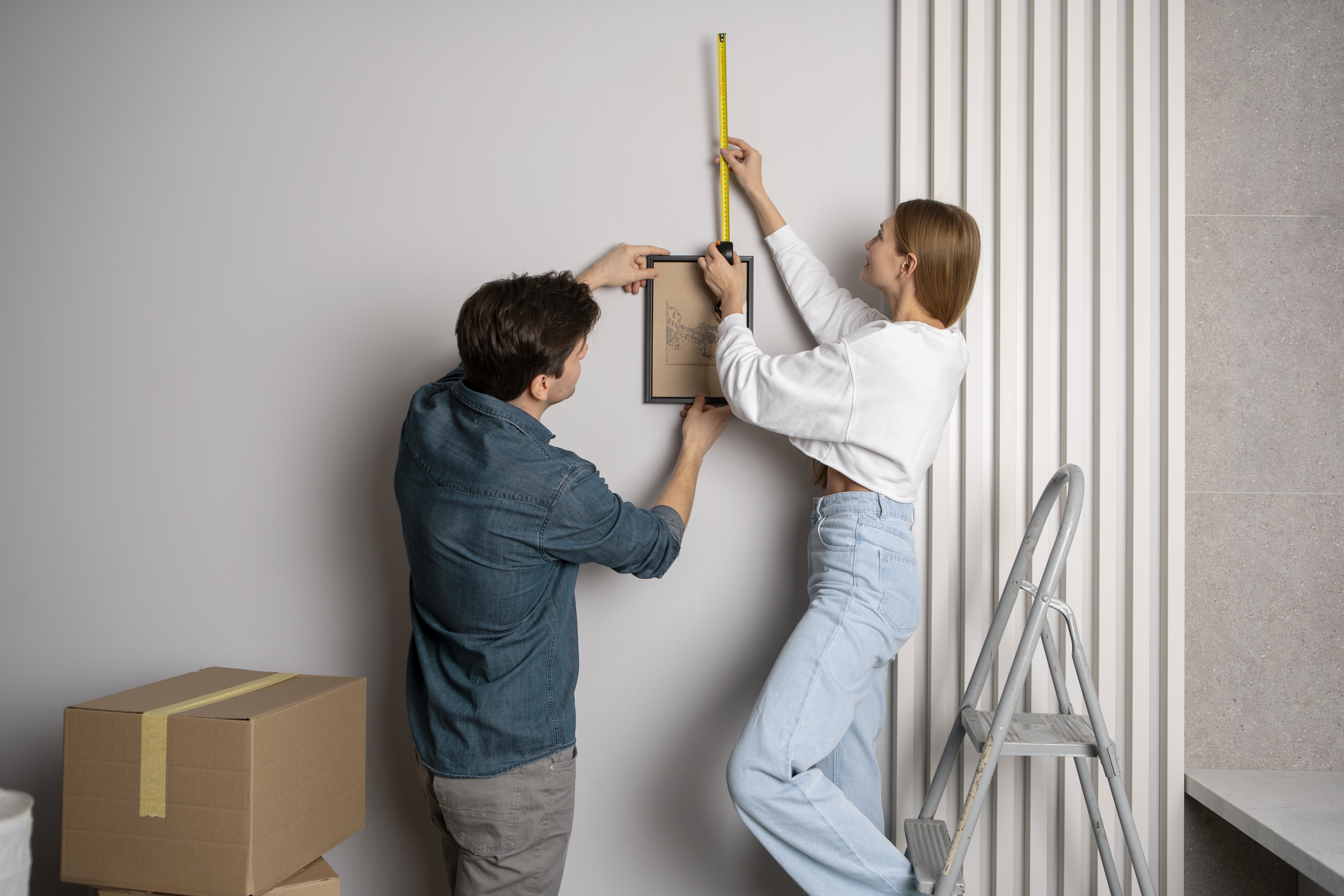 couple measuring wall before hanging frame