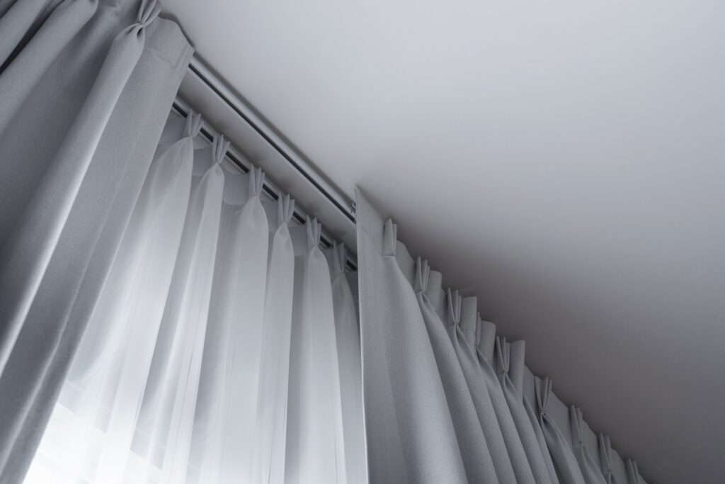 Double white ceiling rail curtain rods in a minimalist arrangement with white curtains